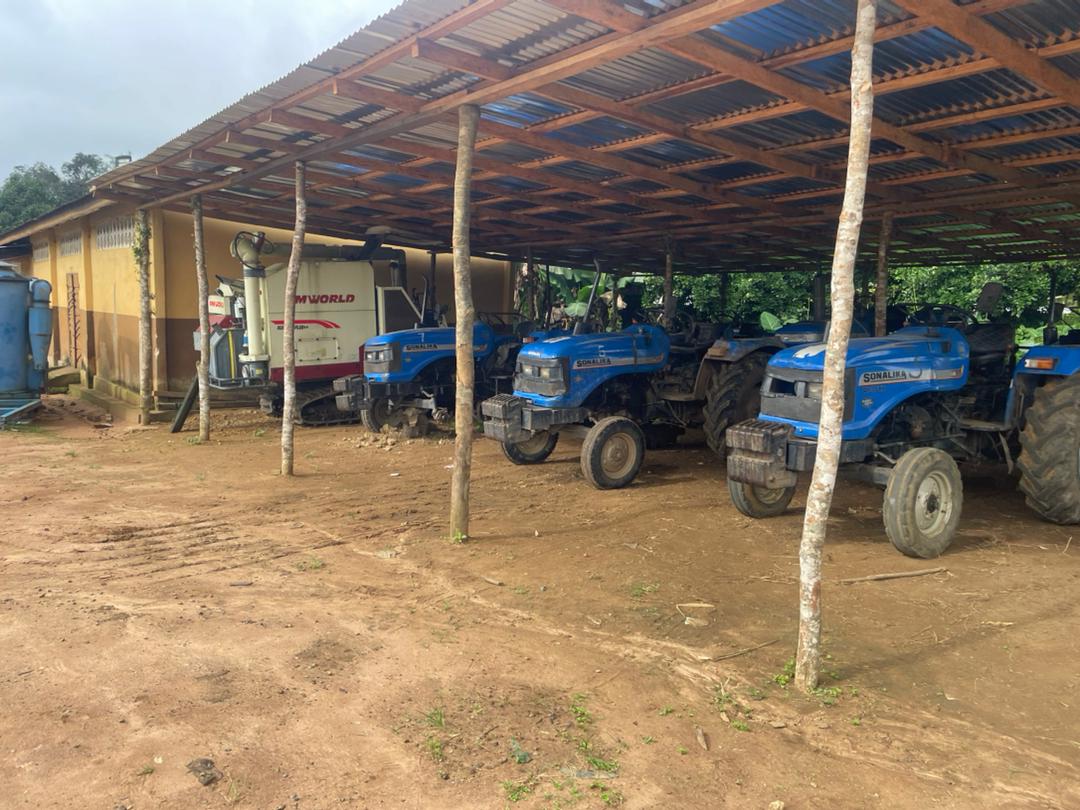 Modern agricultural machinery including combine harvesters and tractors under storage shelter